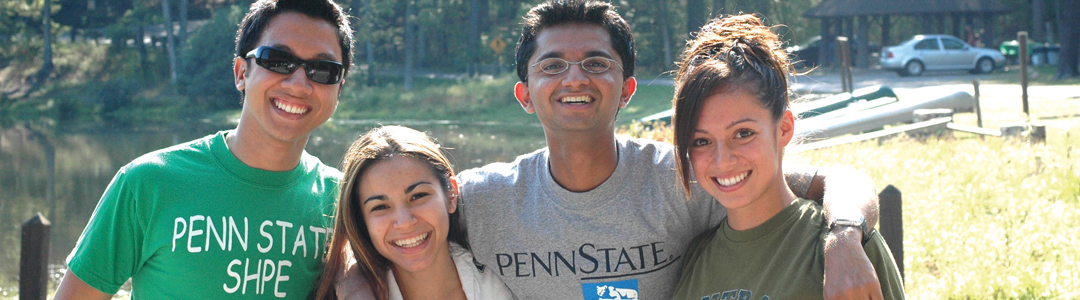 four college aged students standing outside together