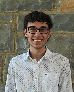 juan gamo standing against a brick stone wall